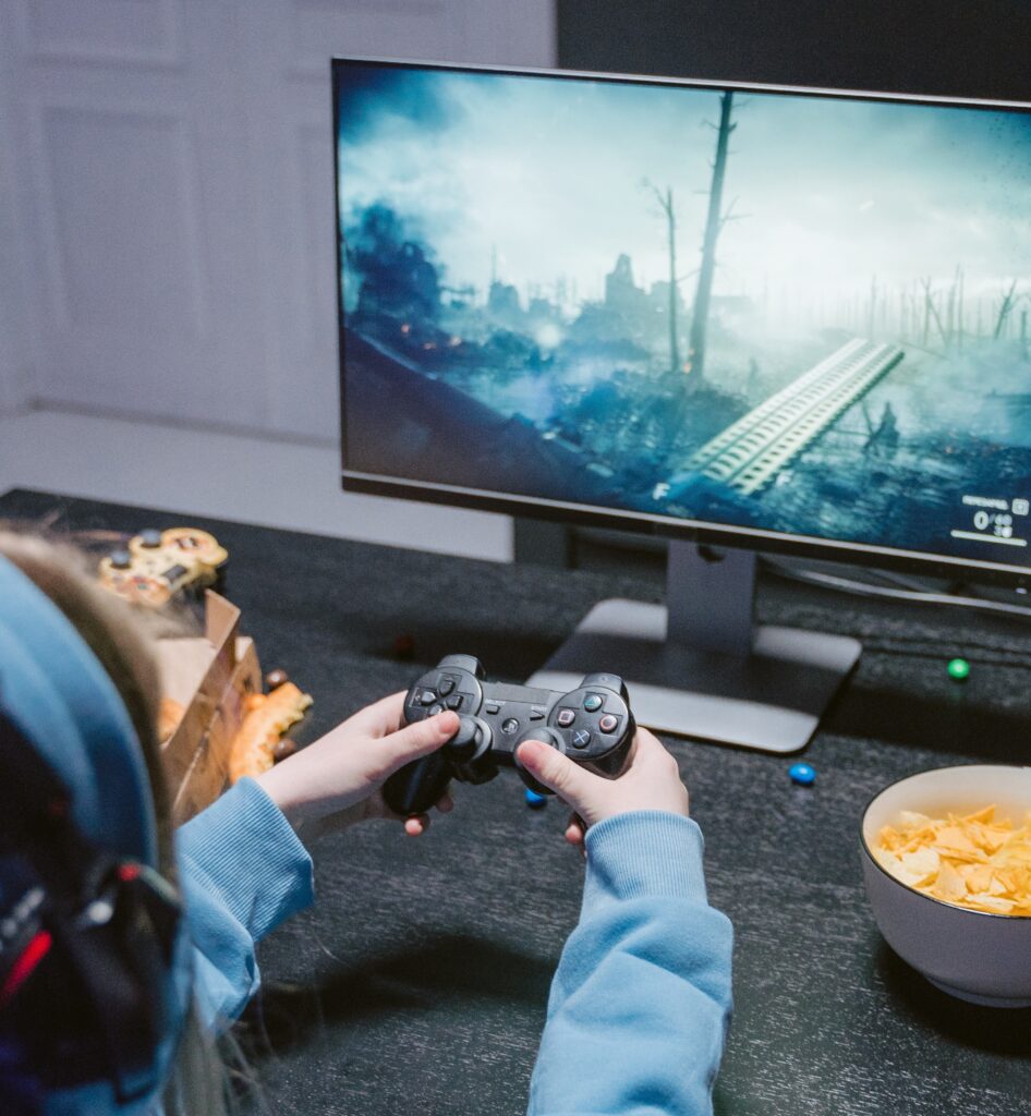 A person holding a controller and gaming in front of a monitor.