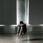 Man sitting on a chair with his head buried in his arms.